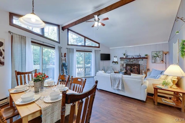 dining area featuring lofted ceiling with beams, wood finished floors, a fireplace, and ceiling fan