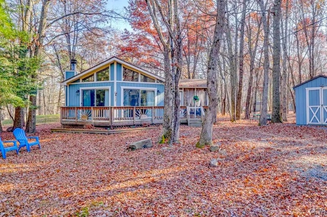 rear view of house with a deck and a storage unit