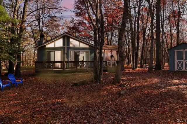 back house at dusk featuring a storage unit and a deck