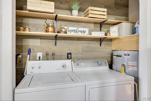 laundry area with laundry area, independent washer and dryer, electric water heater, and wooden walls