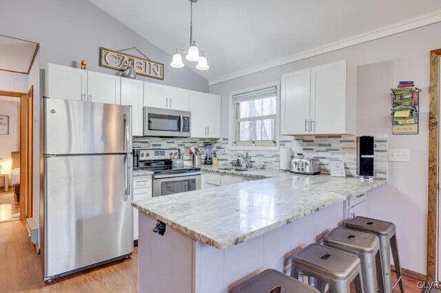 kitchen with stainless steel appliances, a peninsula, and white cabinets