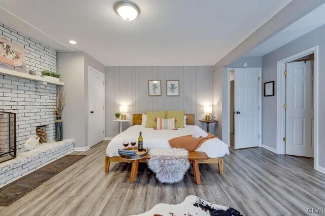 bedroom with wood walls, hardwood / wood-style flooring, and a fireplace