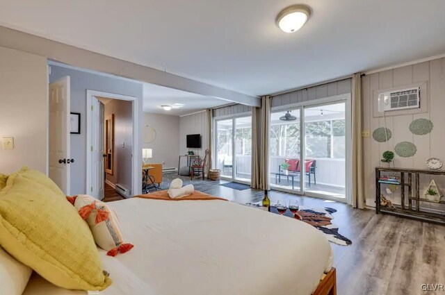 bedroom with wood-type flooring, a baseboard radiator, access to exterior, and an AC wall unit