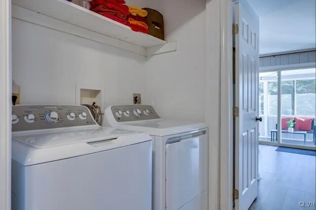 laundry room with washing machine and dryer and light hardwood / wood-style floors