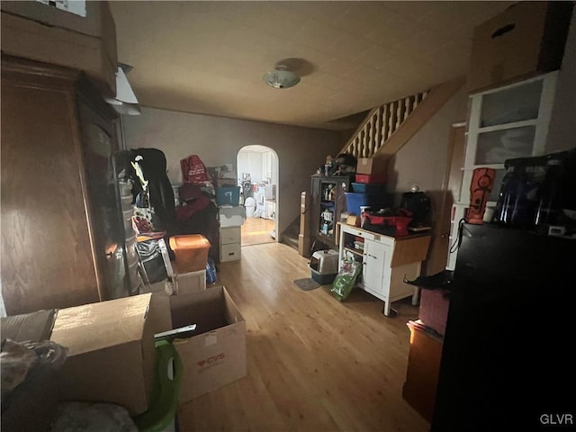 interior space featuring arched walkways, stairs, and wood finished floors