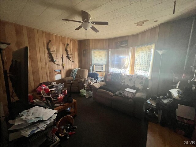 living area with a ceiling fan and wood walls