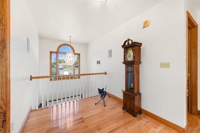 hallway featuring a notable chandelier and light wood-type flooring