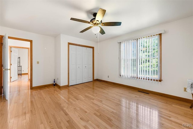 unfurnished bedroom with light wood-type flooring, ceiling fan, and a closet