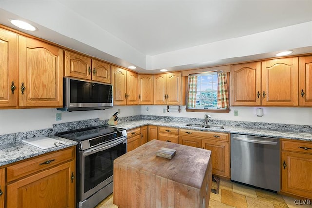 kitchen featuring a kitchen island, stainless steel appliances, light stone counters, and sink