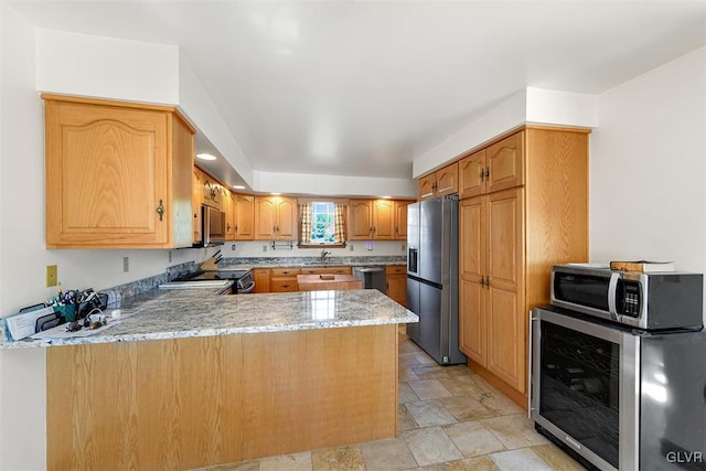 kitchen featuring wine cooler, stainless steel appliances, kitchen peninsula, sink, and light stone countertops