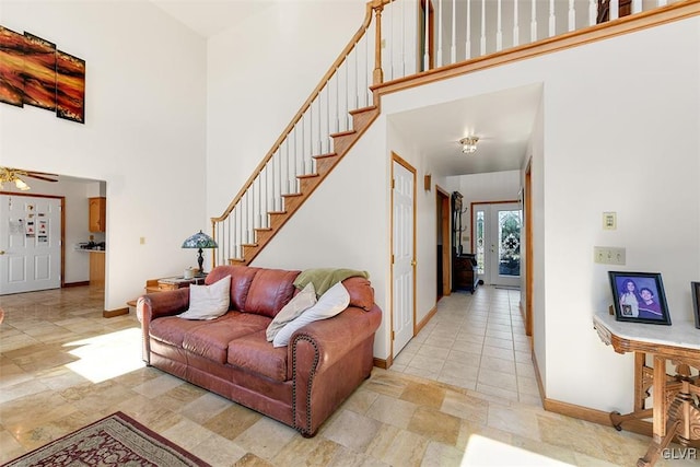 living room with ceiling fan and a towering ceiling