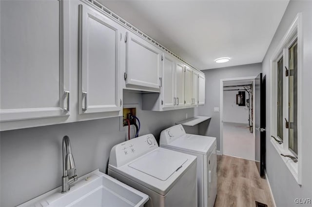 laundry room with cabinets, sink, independent washer and dryer, and light hardwood / wood-style flooring