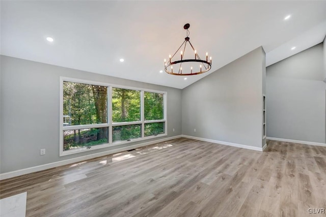 spare room with light hardwood / wood-style flooring, a wealth of natural light, and vaulted ceiling