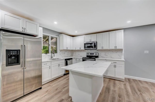 kitchen with light stone countertops, light hardwood / wood-style floors, stainless steel appliances, sink, and white cabinetry