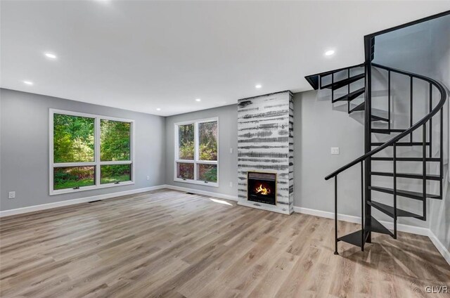 unfurnished living room with a large fireplace and light wood-type flooring