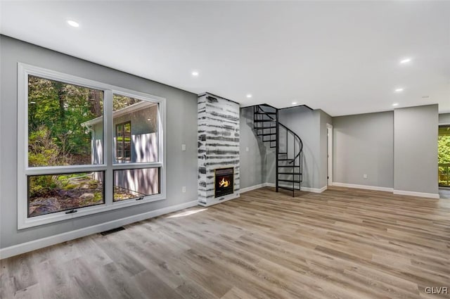 unfurnished living room with a large fireplace and light hardwood / wood-style floors