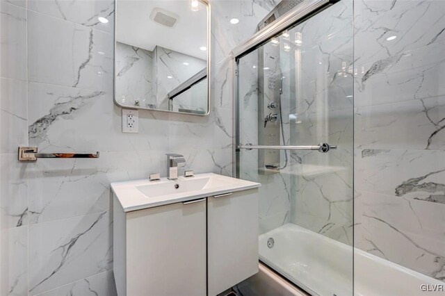 bathroom featuring vanity, tile walls, and enclosed tub / shower combo