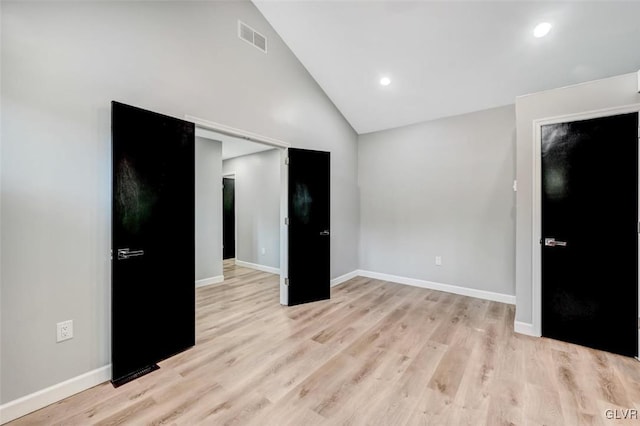 empty room with light wood-type flooring and high vaulted ceiling