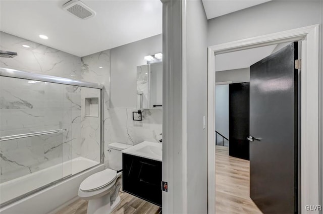 full bathroom featuring hardwood / wood-style floors, enclosed tub / shower combo, toilet, and vanity