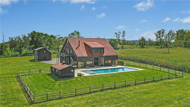 exterior space featuring a fenced in pool, a yard, an outbuilding, and a rural view