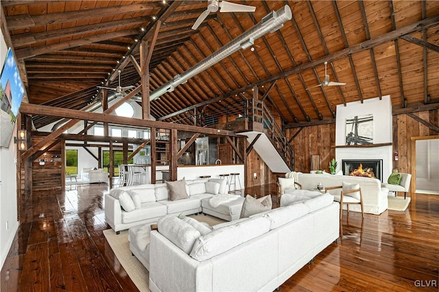 unfurnished living room featuring high vaulted ceiling, wood-type flooring, wood walls, and ceiling fan