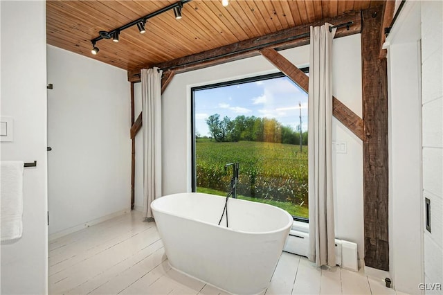 bathroom with a tub, rail lighting, and wooden ceiling