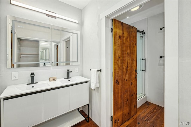 bathroom featuring a shower with shower door, hardwood / wood-style flooring, and vanity