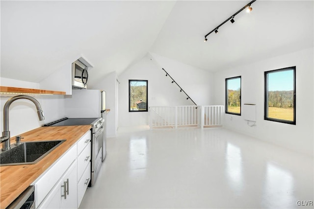 kitchen featuring plenty of natural light, stainless steel appliances, wooden counters, and white cabinetry