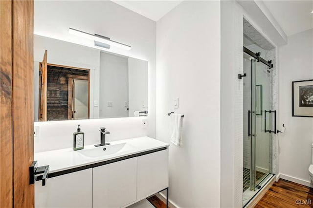 bathroom with a shower with door, vanity, toilet, and wood-type flooring