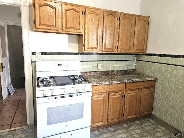 kitchen featuring decorative backsplash, tile walls, and white range with gas stovetop