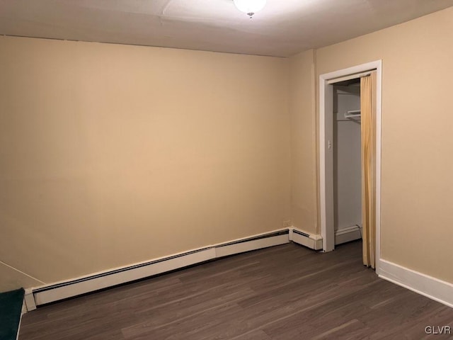 unfurnished bedroom with dark hardwood / wood-style flooring and a baseboard heating unit