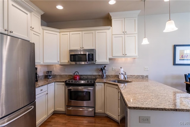 kitchen with dark wood-type flooring, sink, white cabinets, stainless steel appliances, and decorative light fixtures