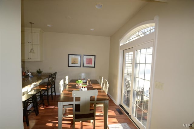 dining area featuring wood-type flooring, lofted ceiling, and sink