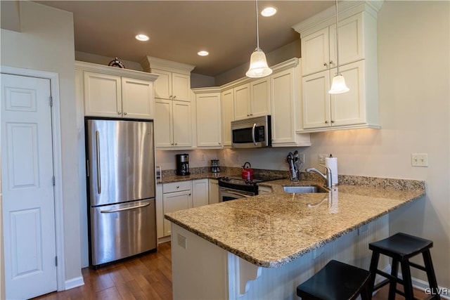 kitchen featuring pendant lighting, a breakfast bar, kitchen peninsula, stainless steel appliances, and dark hardwood / wood-style flooring