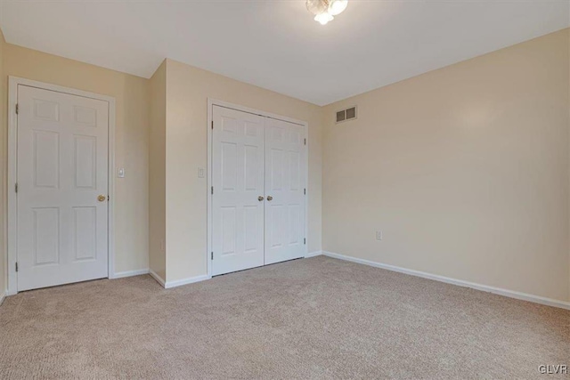 unfurnished bedroom featuring light colored carpet and a closet