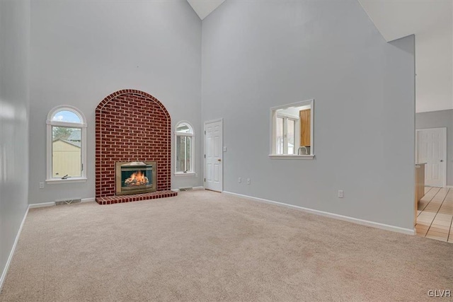 unfurnished living room featuring light colored carpet, a fireplace, and high vaulted ceiling