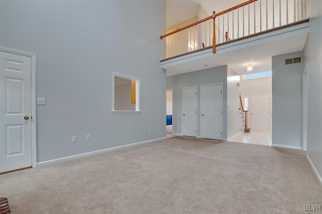 unfurnished living room with light carpet and a high ceiling