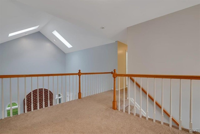 hall featuring light colored carpet and vaulted ceiling with skylight