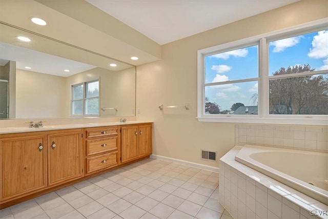 bathroom featuring tile patterned flooring, vanity, and a relaxing tiled tub