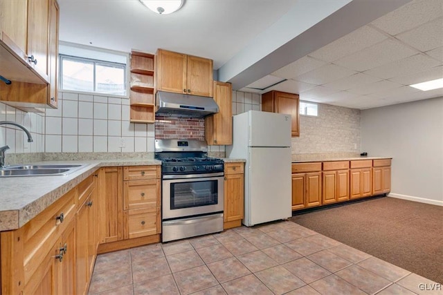 kitchen with backsplash, gas range, sink, light tile patterned floors, and white fridge