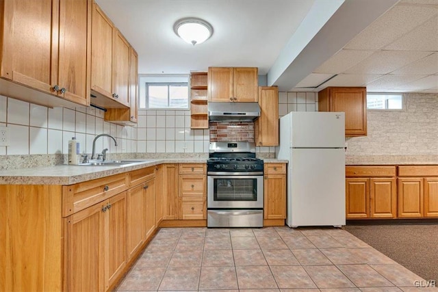 kitchen featuring stainless steel gas range oven, a wealth of natural light, sink, and white refrigerator