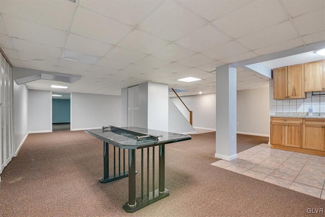 recreation room featuring a paneled ceiling and light colored carpet