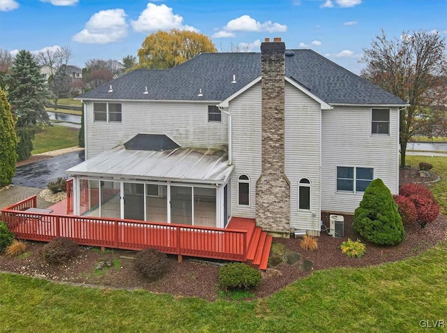 back of property featuring central air condition unit, a wooden deck, a lawn, and a sunroom