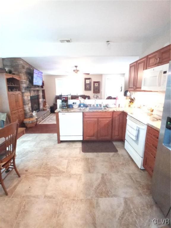 kitchen with white appliances, a fireplace, plenty of natural light, and kitchen peninsula