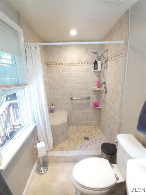 bathroom featuring curtained shower, tile patterned flooring, toilet, and a wealth of natural light