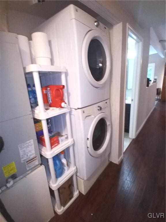 laundry room featuring dark hardwood / wood-style flooring and stacked washing maching and dryer