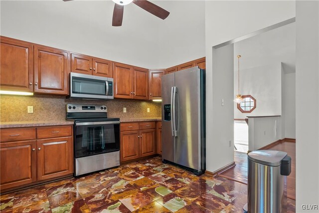 kitchen with dark hardwood / wood-style floors, decorative backsplash, stainless steel appliances, light stone countertops, and ceiling fan