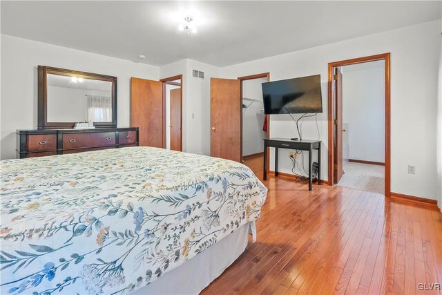 bedroom with wood-type flooring, a closet, and a walk in closet