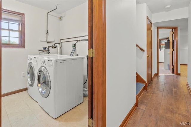 clothes washing area with light hardwood / wood-style floors and washing machine and dryer