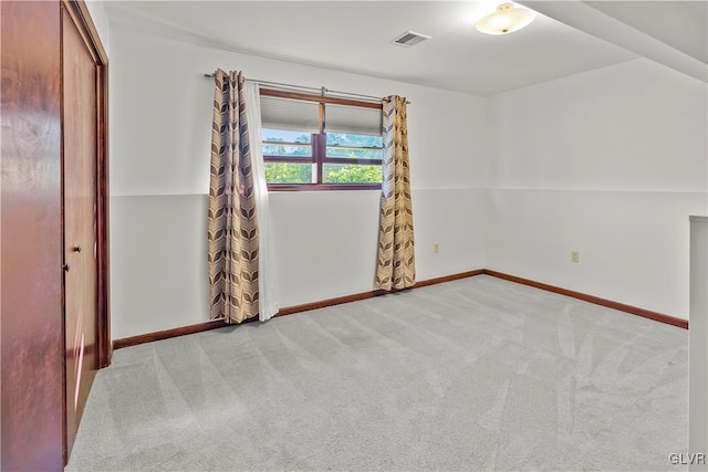 spare room featuring vaulted ceiling and light carpet